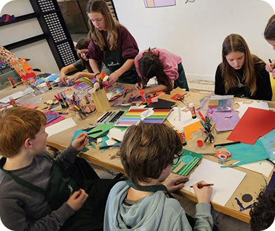 Kinnderen aan een tekentafel waar ze de kaarten aan het ontwerpen zijn